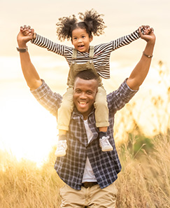 Daughter on fathers shoulders in open field