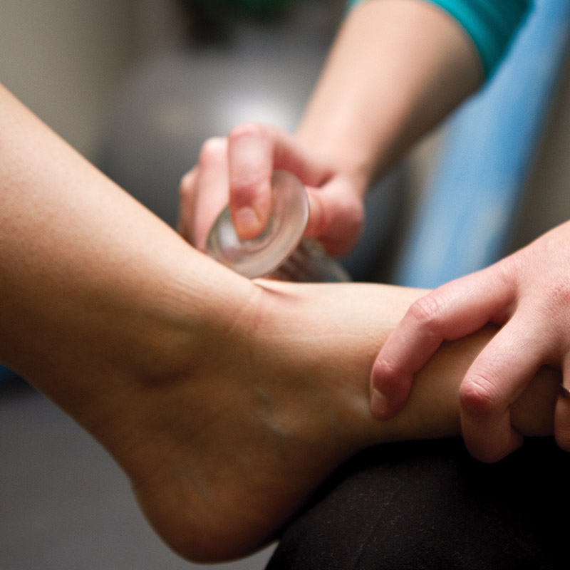 physical therapist works on a patient's foot using ASTYM