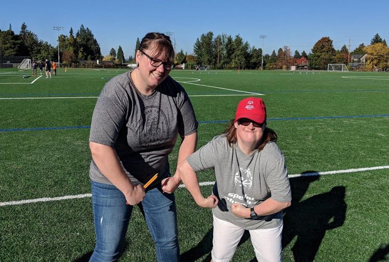 A volunteer and a participant of the Special Olympics flex for the camera