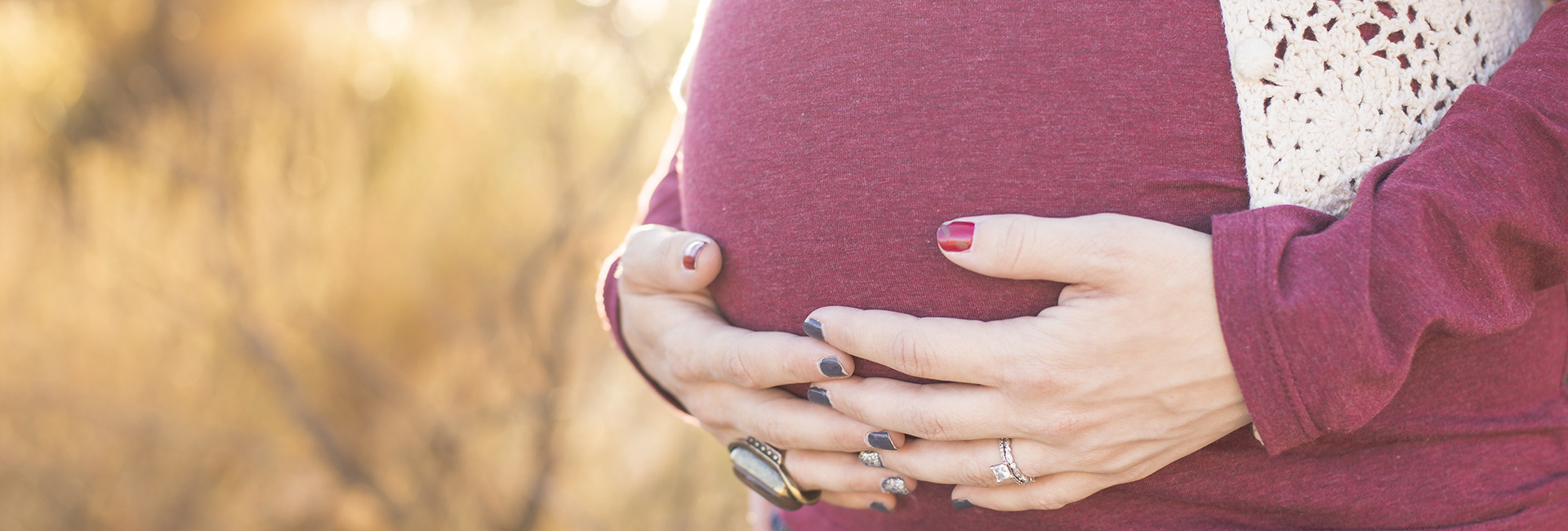 close up of a woman holding her pregnant belly