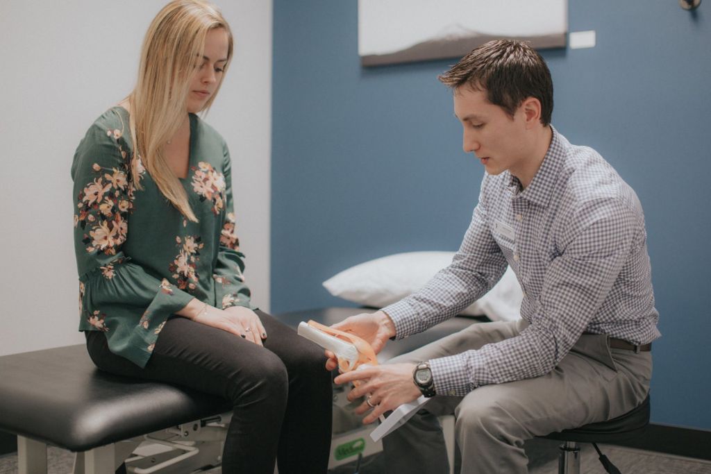 A physical therapist uses a prop to show a patient what is happening with their knee