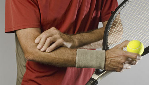 A man holds his elbow during a tennis match