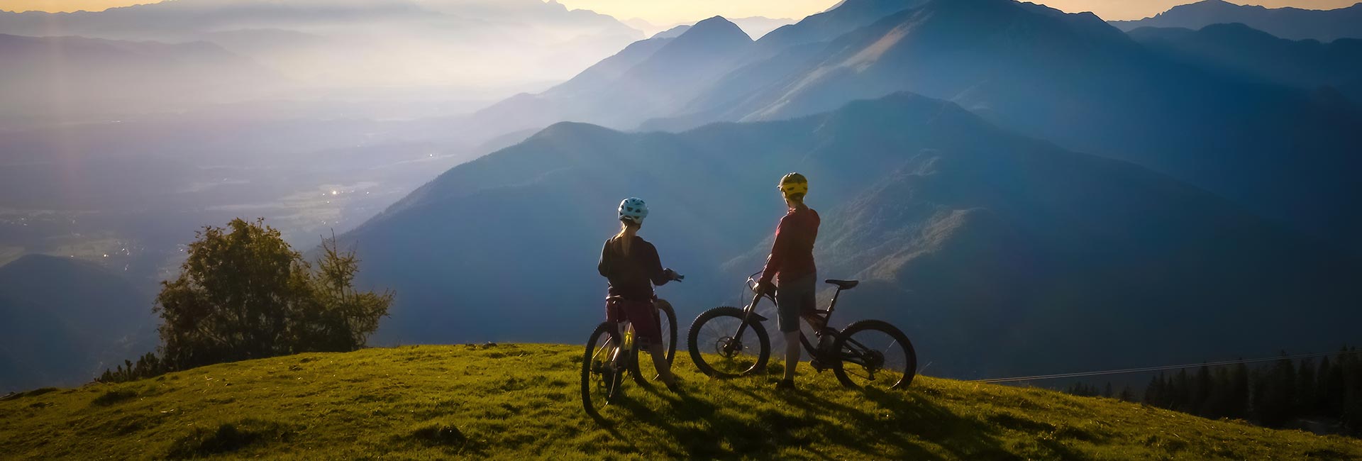 a couple on their mountain bikes a the top of a hill taking in the vast landscape view