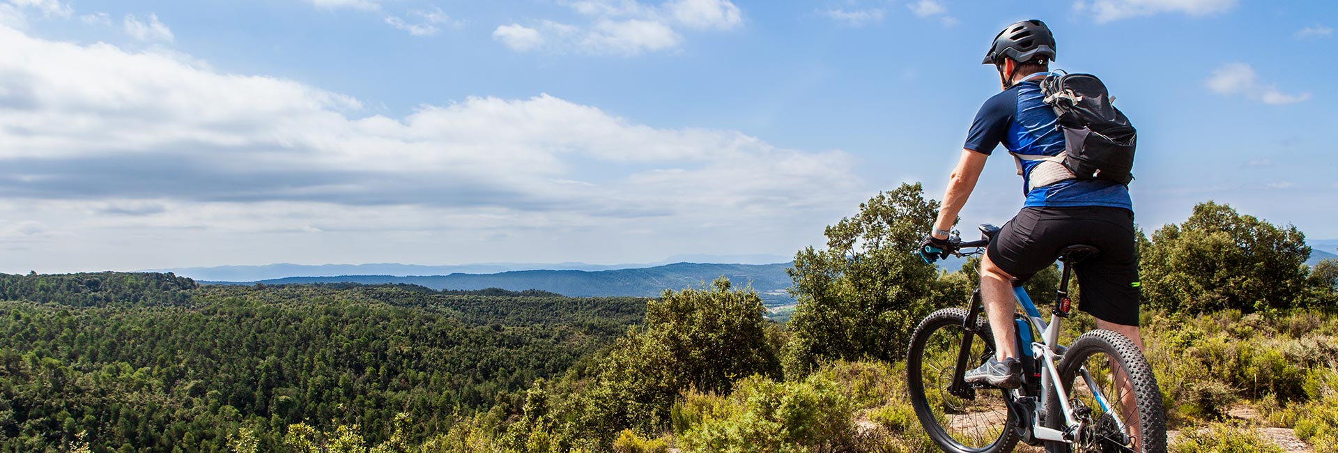 rear view of a mountain biker taking in the view at the top of a hill