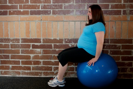 A physical therapist assists a pregnant patient with pelvic floor exercise for pre-partum care.