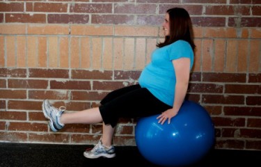 A physical therapist assists a pregnant patient with pelvic floor exercise for pre-partum care.