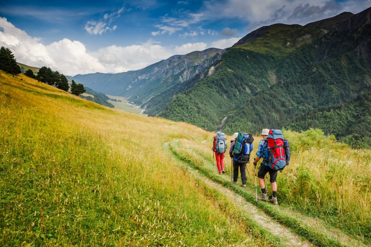 A group of three people hiking into the wilderness on a backpacking excursion
