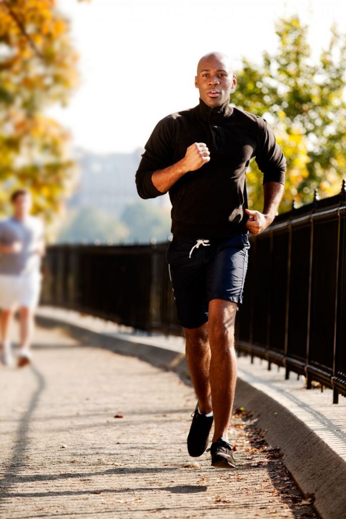 young fit man running on a pathway in town in the fall