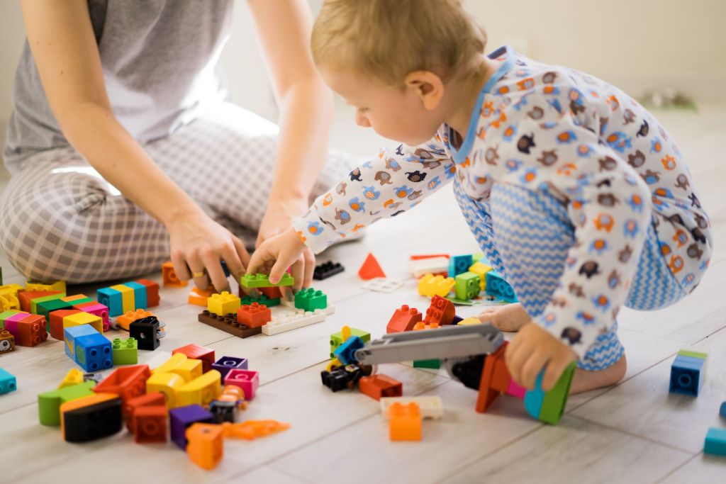 A toddler plays with building blocks on the floor