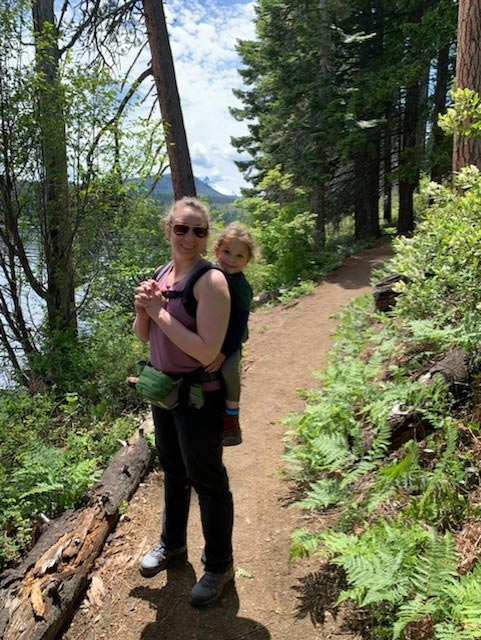 A woman with a child in a backpack on a hiking trail