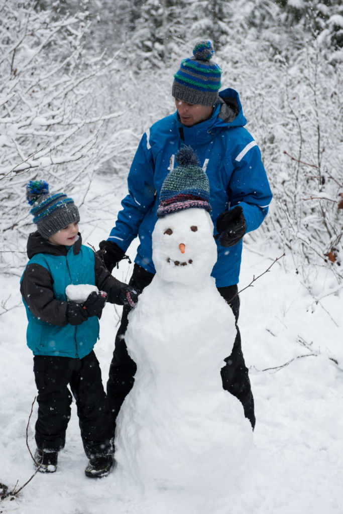 man and son build snowman