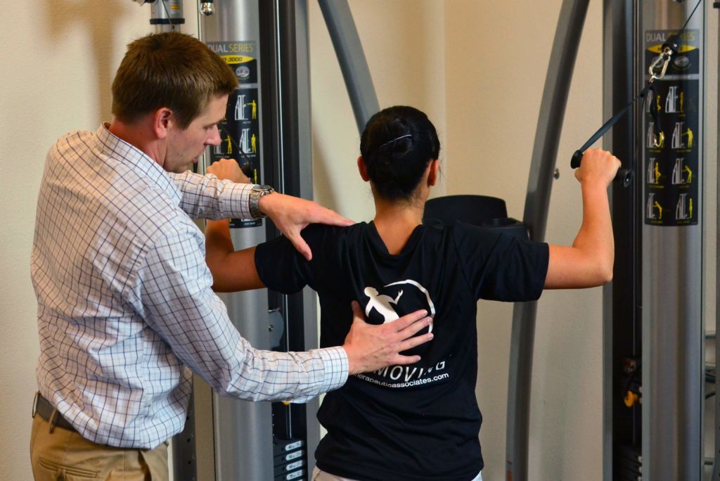 physical therapist works with patient on back strength