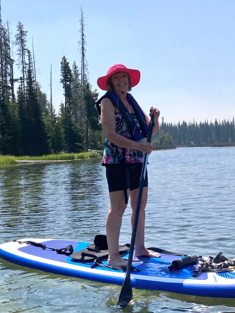 older woman smiling while stand up paddle boarding