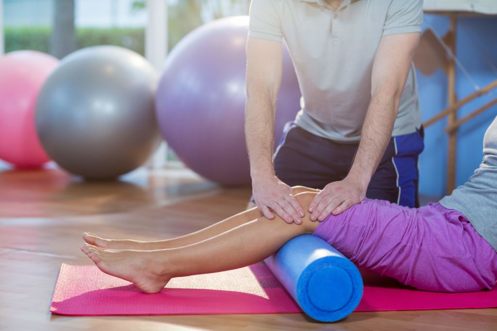 close up of a PT working a patient's knees utilizing foam roller
