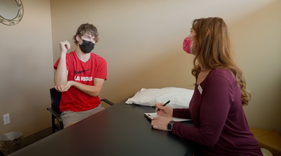 physical therapist takes notes talking to patient