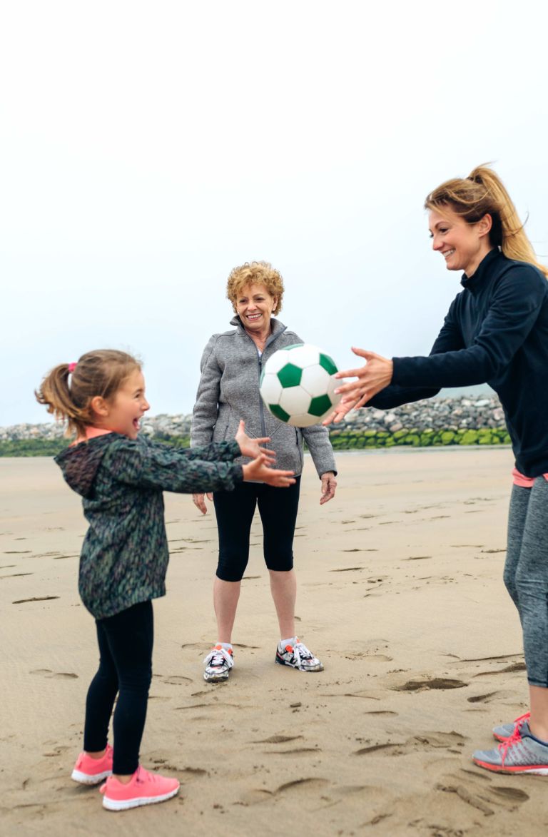 three generations on the beach with a soccer ball