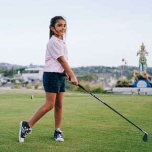 young girl watches her golf ball after a drive