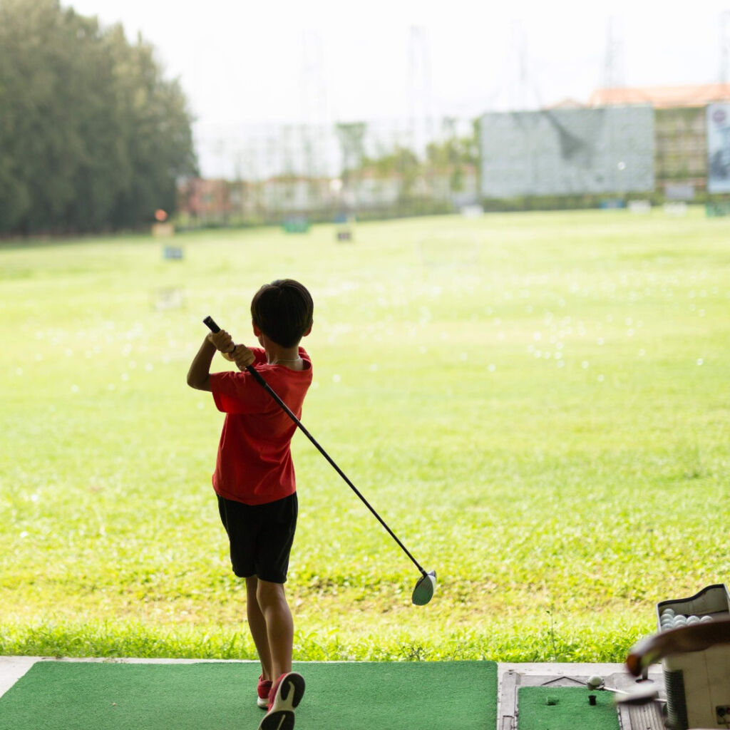 young golfer practices at driving range