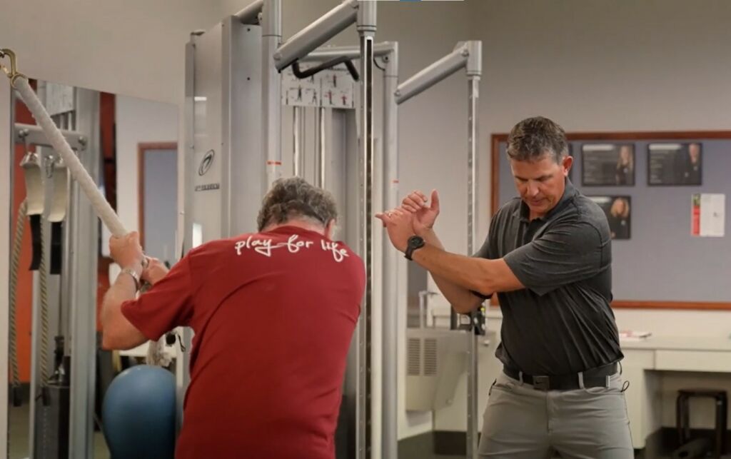 physical therapist guides patient with golf strengthening exercise