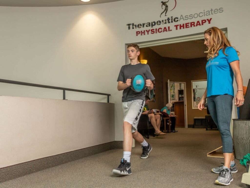 PT helps student athlete with physical therapy exercise