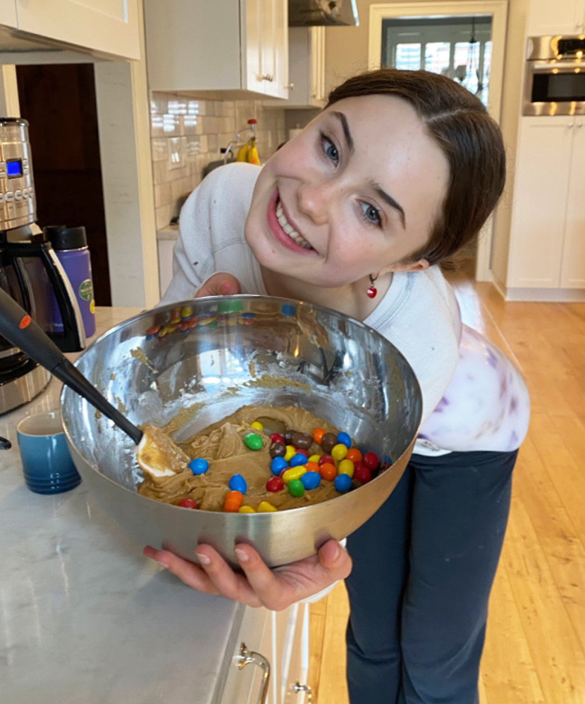 young woman presents a bowl of cookie dough.