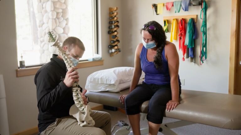 physical therapist explains low back pain using a prop skeleton