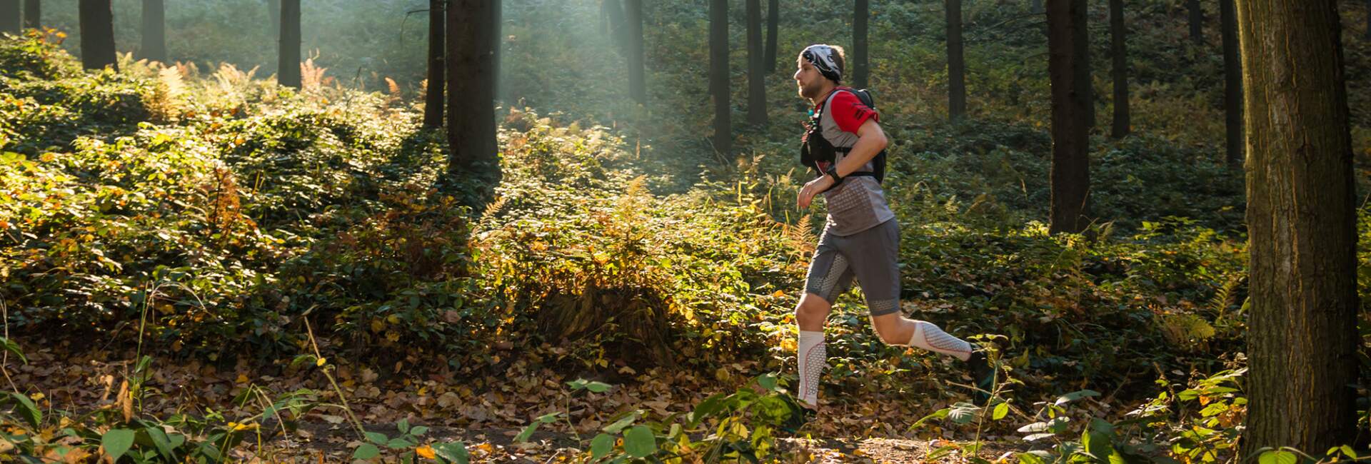 man runs on trail through forest in the autumn