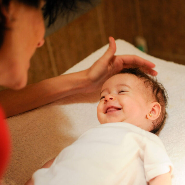 baby smiles up at caregiver