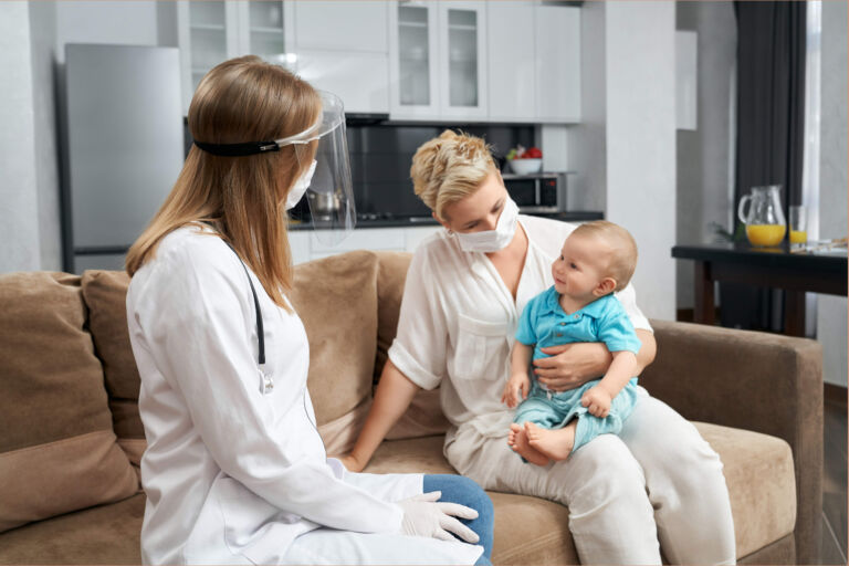 healthcare provider interacts with mother and baby in their home.