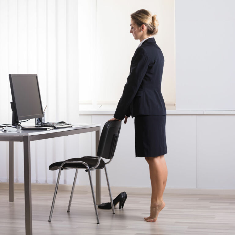 a woman does heel raises at her desk