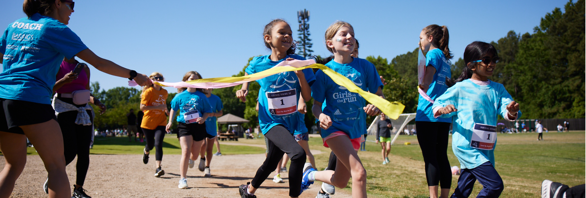 girls cross the finish line at a Girls on the Run 5K running event