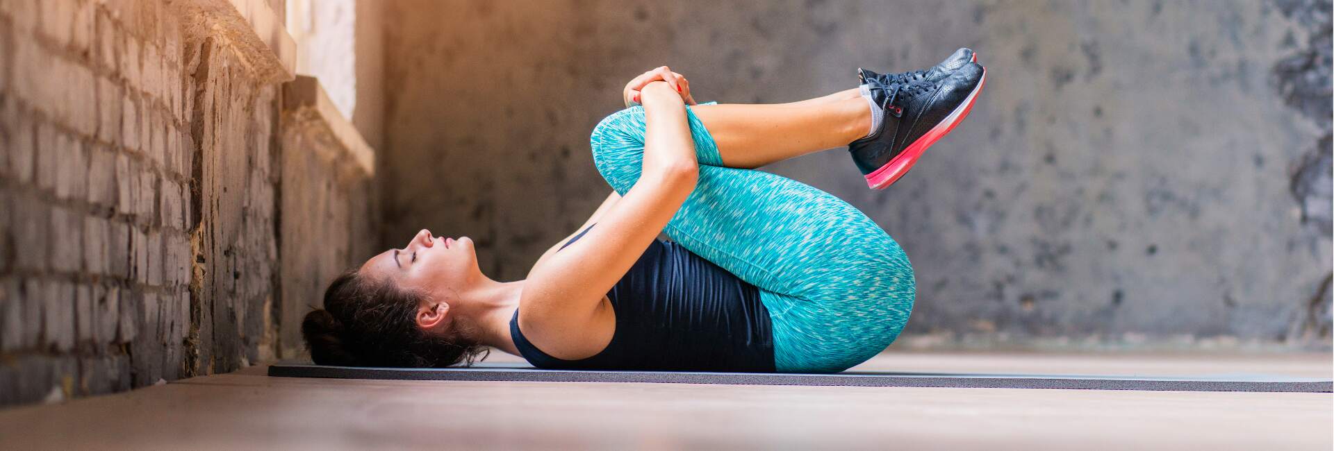 woman lying on back pulling knees to chest in lower back stretch for pain relief