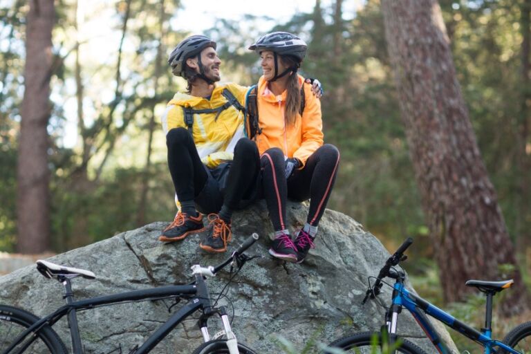 young mountain biking couple sits on a rock taking a break during a bike ride