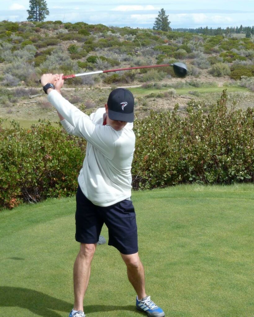 a golfer takes a back swing on a lovely course