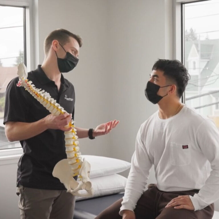 physical therapist uses a spine model to explain a patient's care