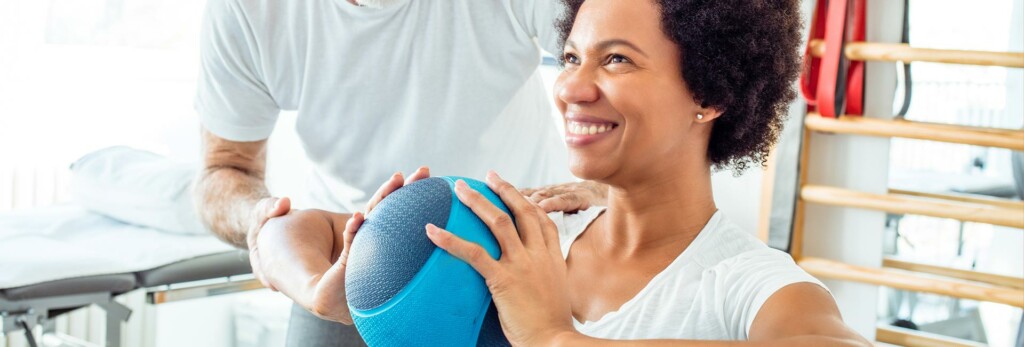 hand therapist assists woman with ball exercise