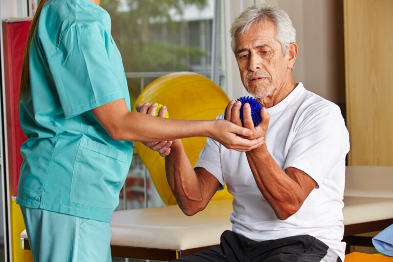 therapist works with a patient on hand strength and grip exercise