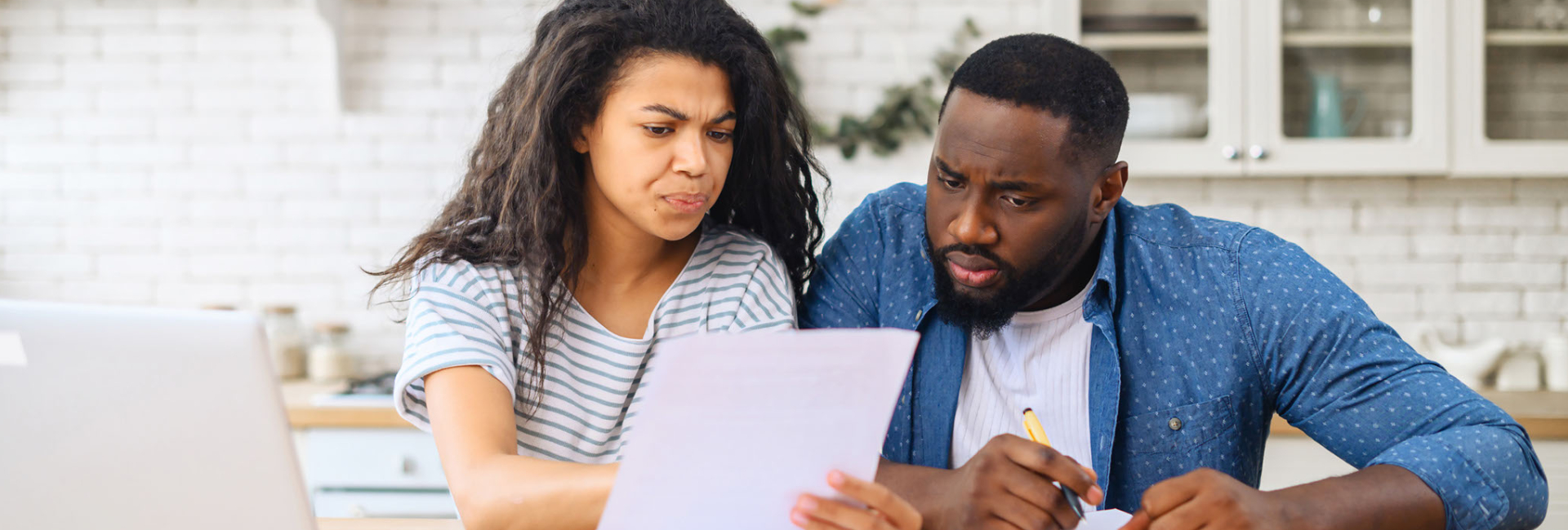 A couple looks over paperwork with confused expressions