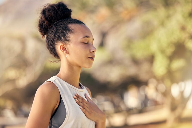 a young black woman places her hand upon her chest to focus on her breathing