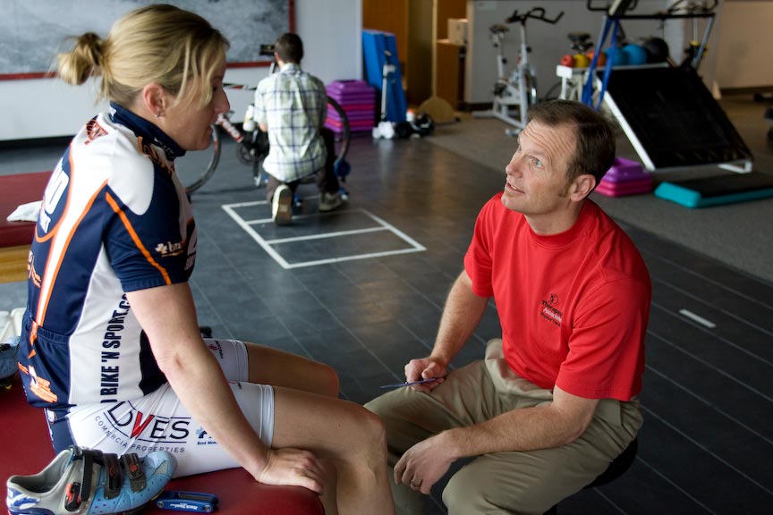 A physical therapist talks with a patient in a clinic.