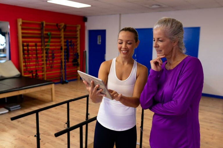 two women in a gym review an ipad