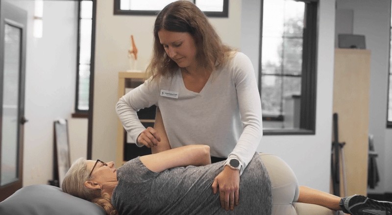 physical therapist performs manual therapy on a patient