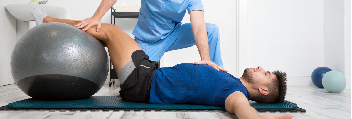 A physical therapist works with a male patient on pelvic floor and core exercises.