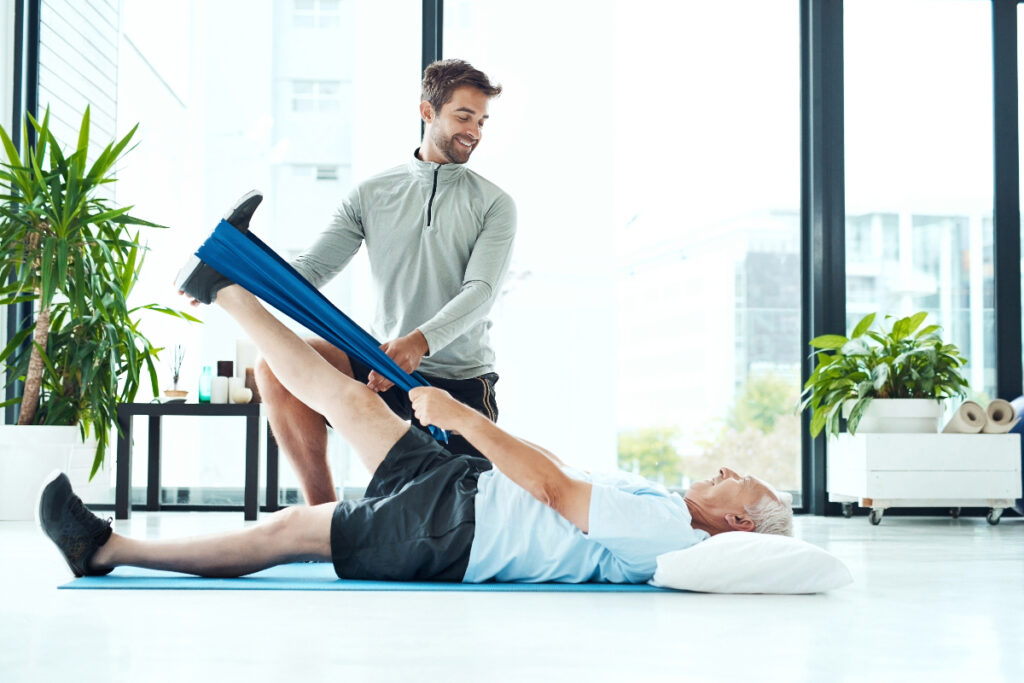 a PT helps an older man with a stretching exercise