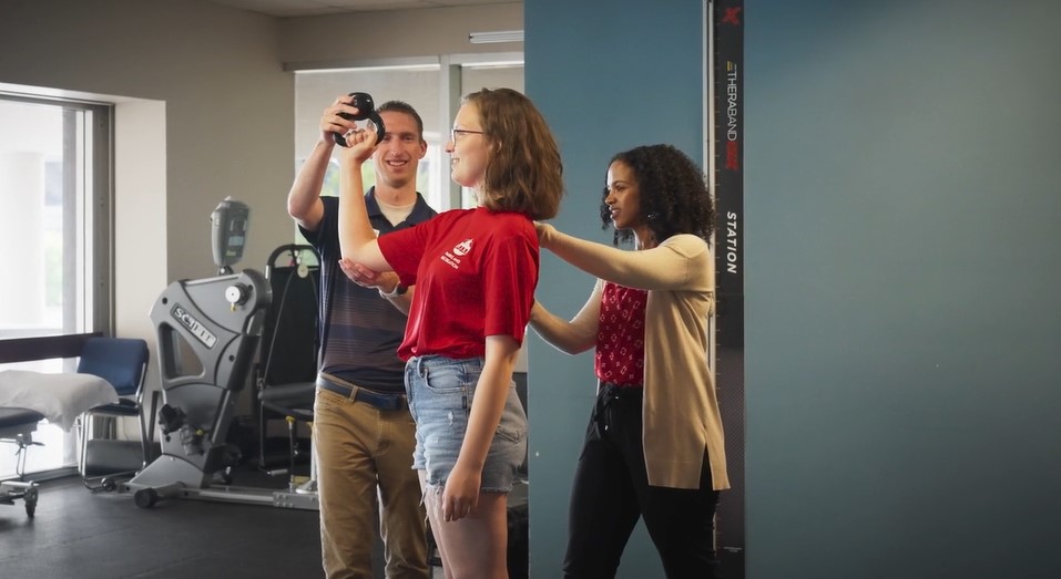 Physical therapists work together to guide a patient during an exercise