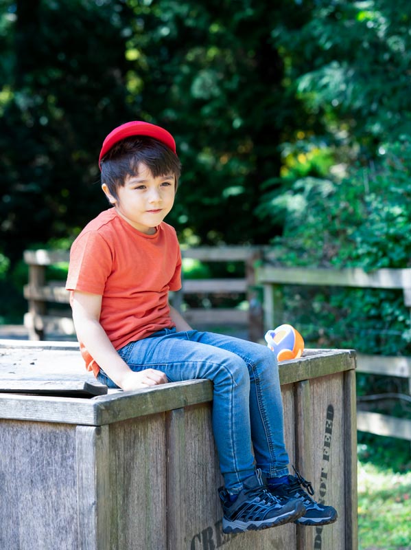young kid sits watching from the side of the park