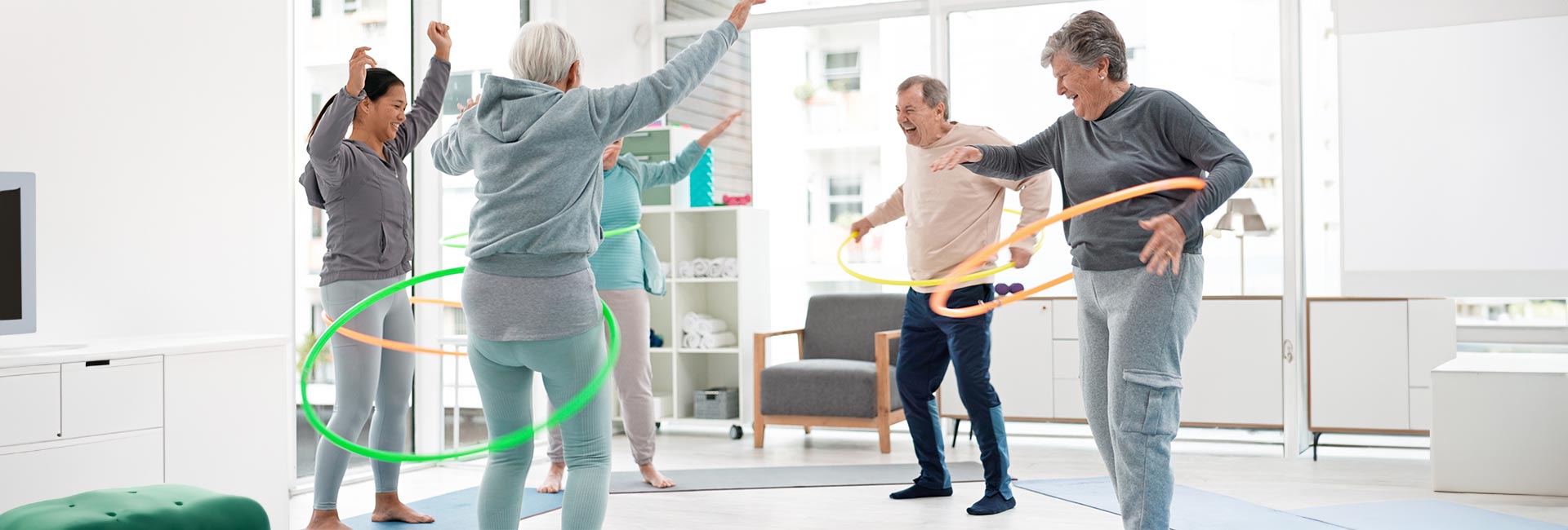 A group of older adults have fun hula hooping for exercise