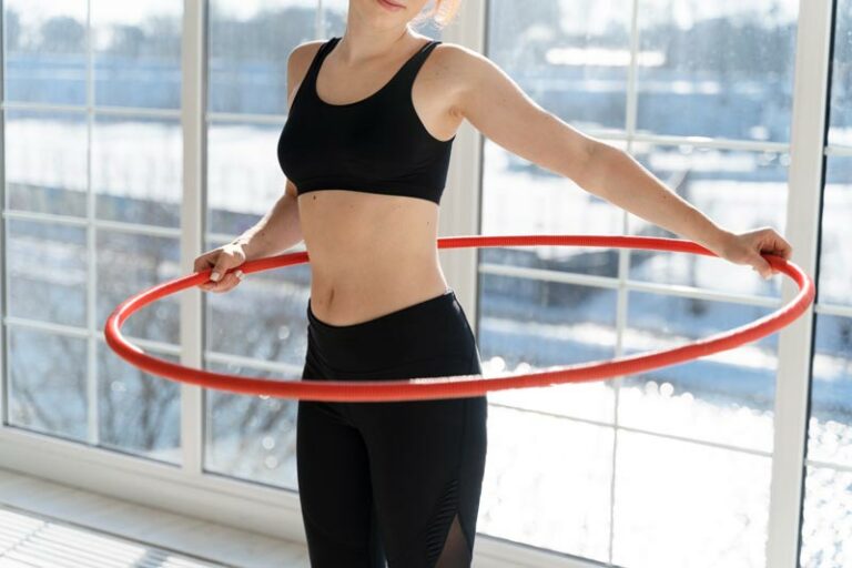 a thin young woman holds a hula hoop ready to begin exercising