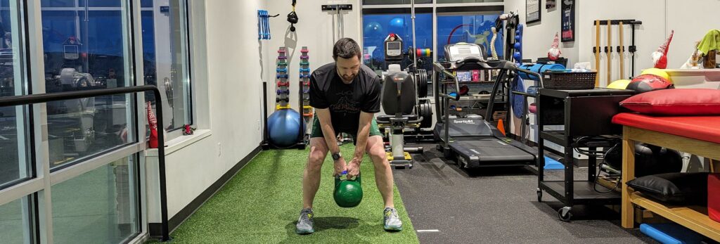 Physical therapist Kyle Stewart demonstrates an exercise utilizing a Kettlebell