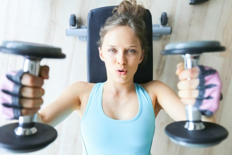 a young woman practices efficient breathing while strength training with dumbbells